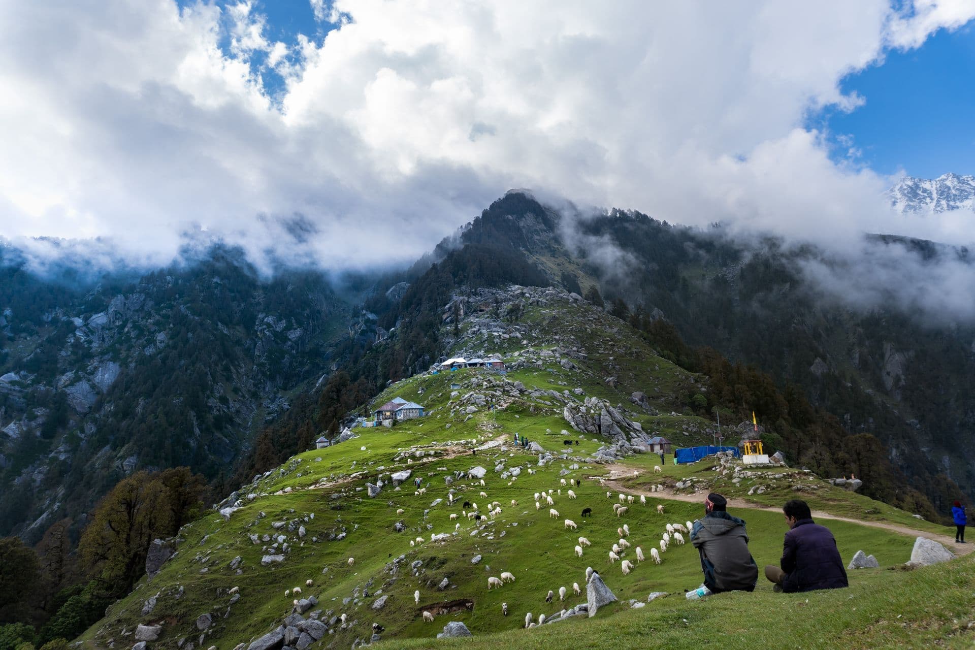 Travellers resting together on the green Triund ridge